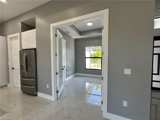 Kitchen featuring a tray ceiling, stainless steel fridge, and white cabinets