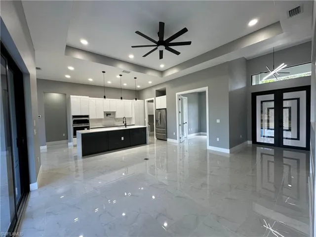 Kitchen featuring sink, white cabinetry, hanging light fixtures, an island with sink, and stainless steel appliances