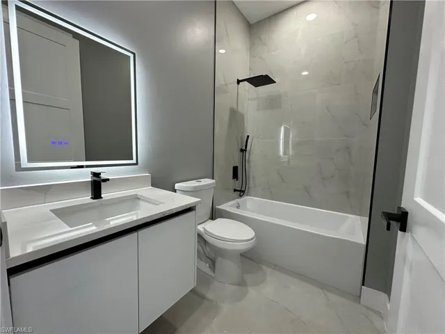 Full bathroom featuring tiled shower / bath, vanity, and toilet