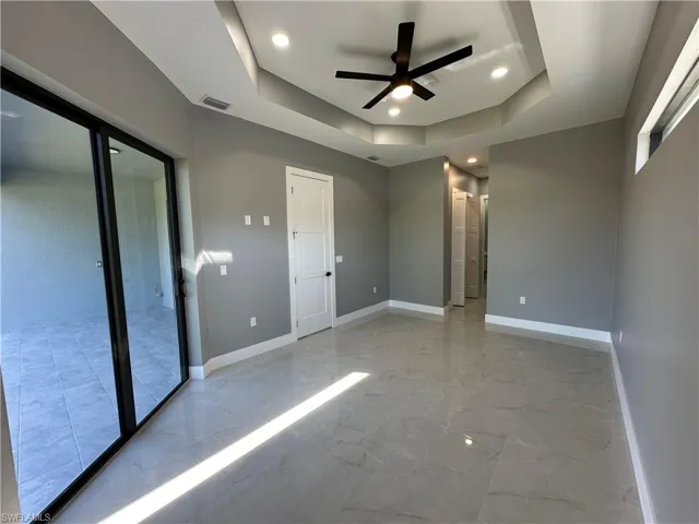 Unfurnished bedroom with a raised ceiling and ceiling fan