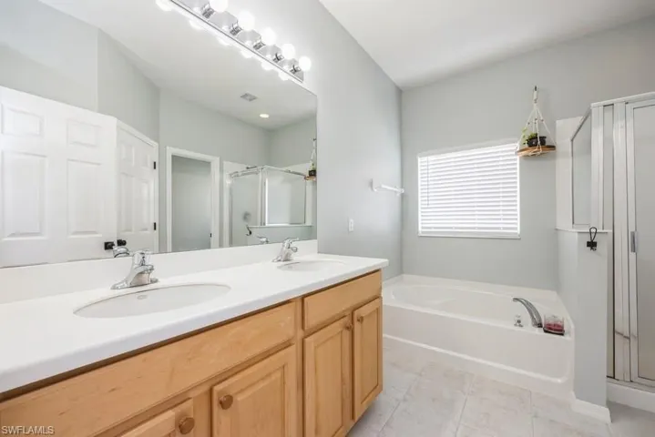 Bathroom featuring tile flooring, double vanity, and plus walk in shower