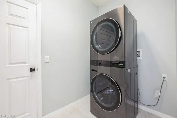Laundry area with hookup for a washing machine, stacked washer / dryer, and light tile flooring