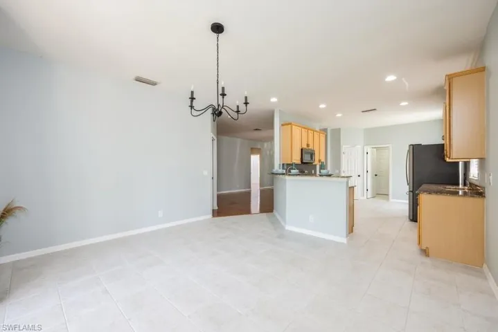 Kitchen featuring a notable chandelier, light tile flooring, decorative light fixtures, and light brown cabinetry