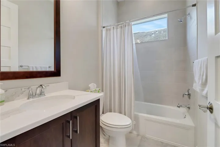 Full bath with tile patterned floors, vanity, toilet, and shower / tub combo with curtain