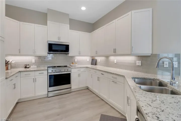 Kitchen featuring white cabinets, backsplash, stainless steel appliances, and a sink