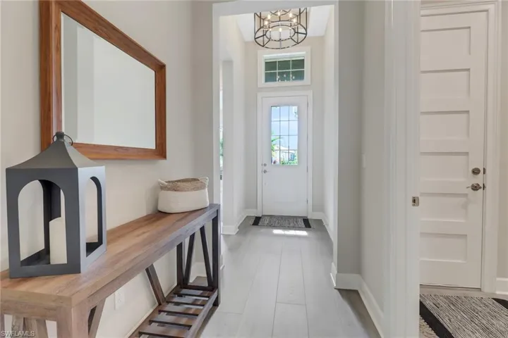 Foyer entrance featuring baseboards, wood finished floors, and an inviting chandelier