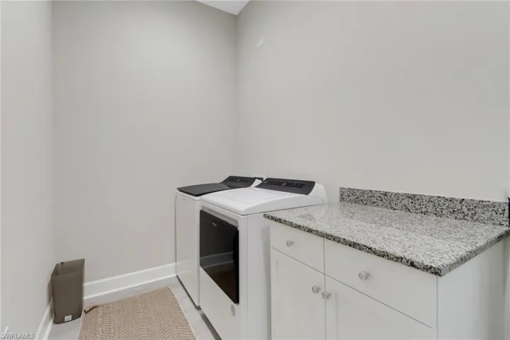 Clothes washing area featuring cabinet space, washer and clothes dryer, and baseboards