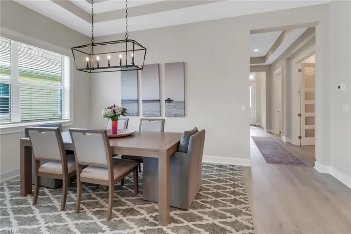 Dining area with recessed lighting, a raised ceiling, baseboards, and wood finished floors