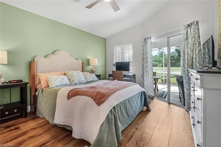 Bedroom featuring ceiling fan, light wood-type flooring, vaulted ceiling, and access to exterior