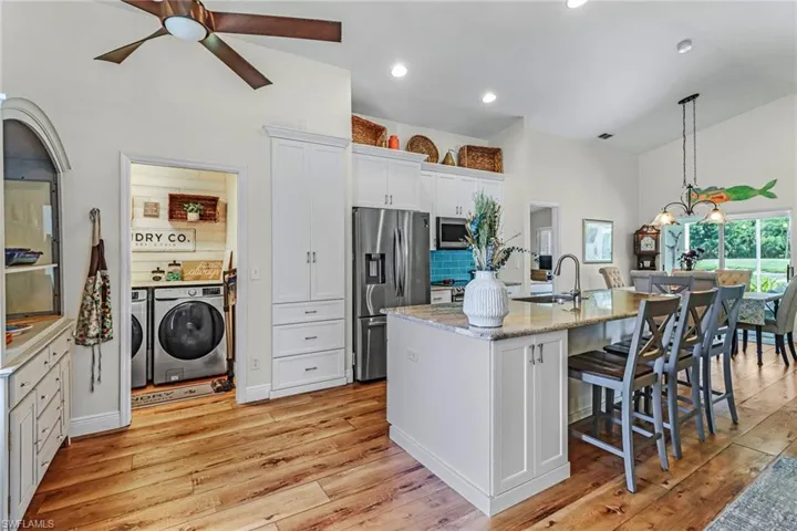 Kitchen with hanging light fixtures, light hardwood / wood-style flooring, appliances with stainless steel finishes, white cabinets, and ceiling fan