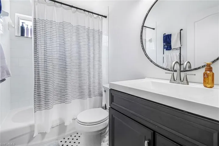 Full bathroom with shower / bath combination with curtain, vanity with extensive cabinet space, tile floors, and toilet