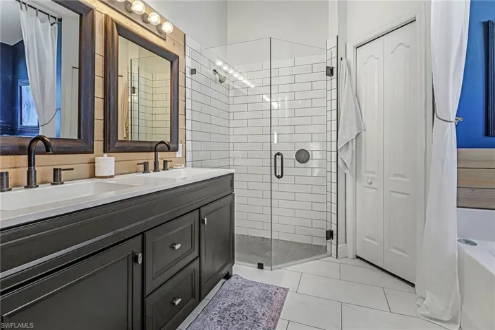 Bathroom featuring a shower with door, dual sinks, tile floors, and large vanity