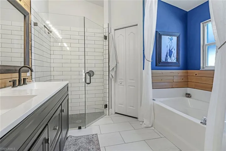 Bathroom featuring separate shower and tub, vanity, and tile floors