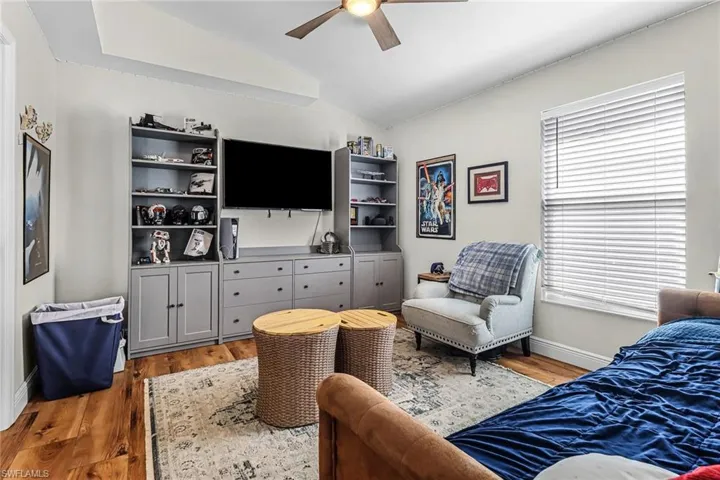 Bedroom with vaulted ceiling, ceiling fan, light wood-type flooring, and multiple windows