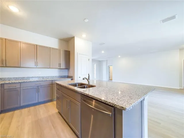 Kitchen with an island with sink, dishwasher, sink, and light hardwood / wood-style flooring