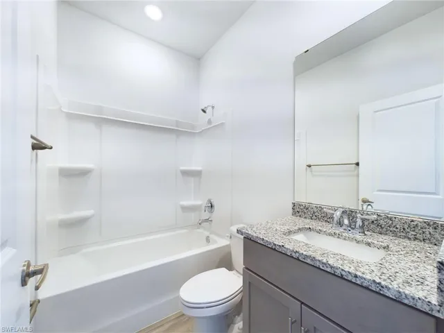 Full bathroom featuring vanity, toilet, shower / bath combination, and hardwood / wood-style floors