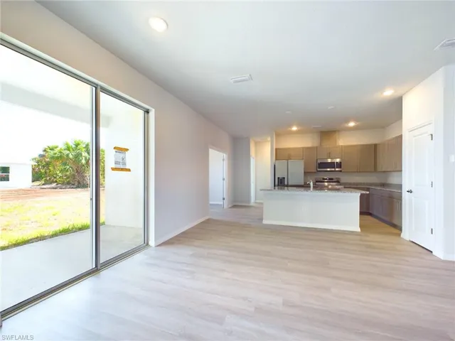 Kitchen featuring light wood-type flooring, stainless steel appliances, sink, and a center island with sink