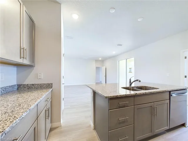 Kitchen featuring light stone counters, sink, gray cabinetry, and light hardwood / wood-style floors