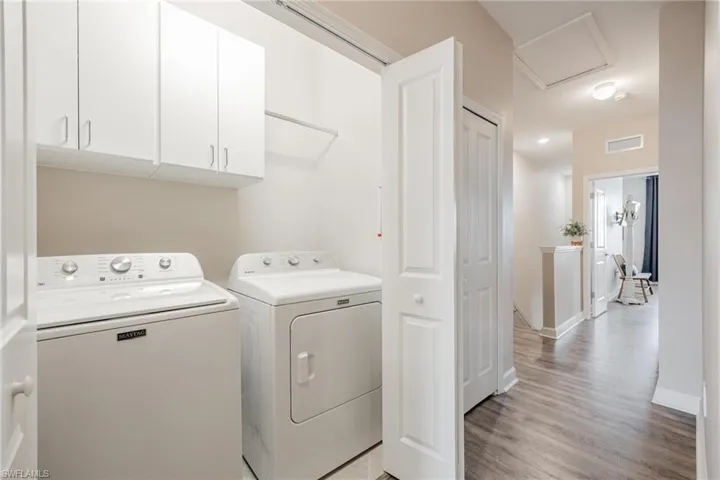 Washroom with light hardwood / wood-style flooring, cabinets, and washer and dryer