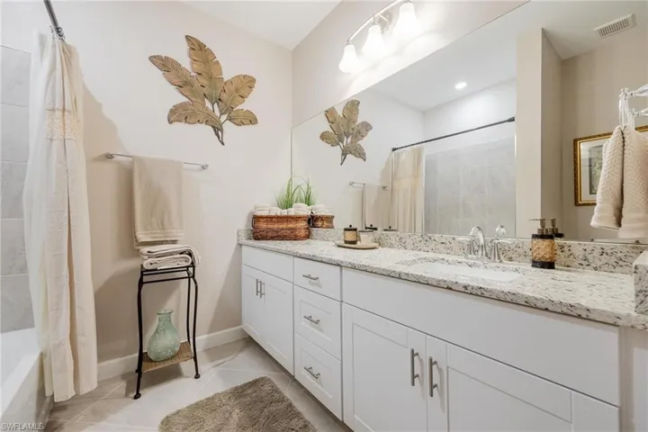 Bathroom with vanity, shower / bath combo with shower curtain, and tile patterned flooring