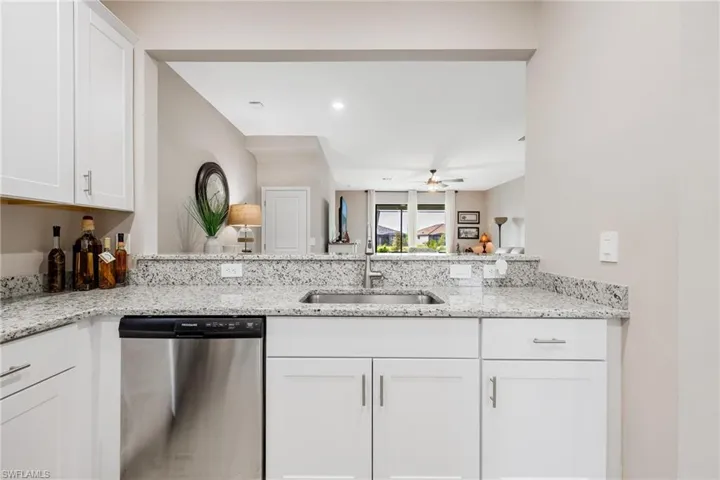 Kitchen featuring light stone countertops, dishwasher, kitchen peninsula, sink, and ceiling fan