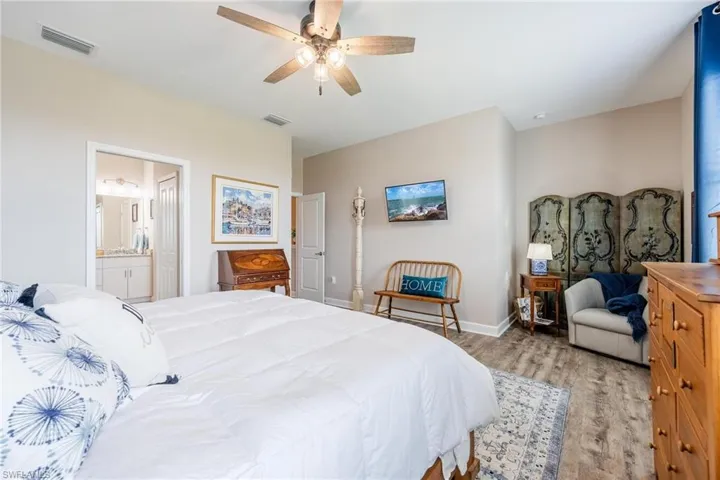 Bedroom featuring ceiling fan, ensuite bath, and light hardwood / wood-style floors