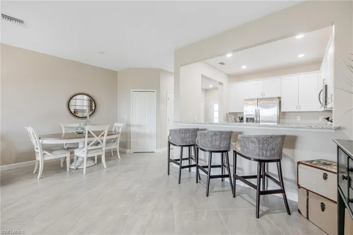 Kitchen with white cabinetry, kitchen peninsula, light stone counters, appliances with stainless steel finishes, and light tile patterned flooring