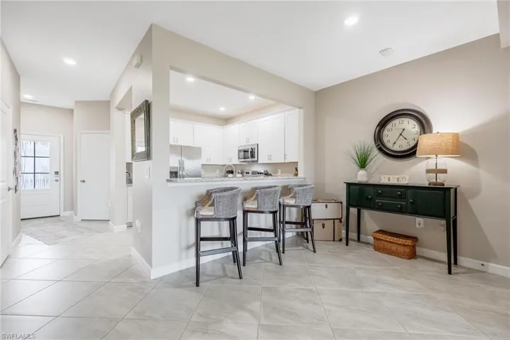 Kitchen with appliances with stainless steel finishes, white cabinetry, light tile patterned floors, and a kitchen breakfast bar