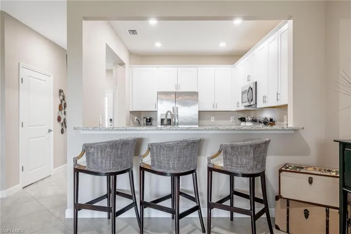 Kitchen featuring a kitchen breakfast bar, light tile patterned floors, appliances with stainless steel finishes, kitchen peninsula, and white cabinets