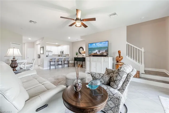 Living room with ceiling fan and light tile patterned flooring