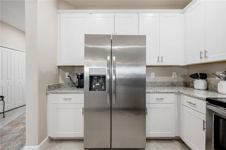 Clubhouse Kitchen featuring light stone countertops, appliances with stainless steel finishes, white cabinetry, and light tile patterned flooring