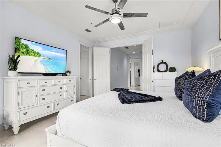 Bedroom featuring a ceiling fan, light marble finish flooring, and crown molding