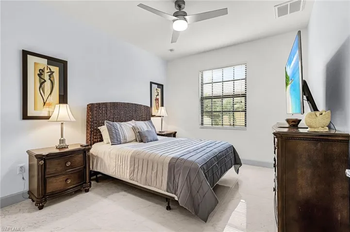 Bedroom with a ceiling fan and light marble finish flooring