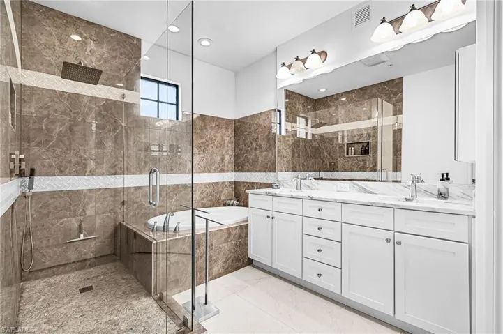 Bathroom with a shower stall, a garden tub, double vanity, light marble finish floors, and recessed lighting