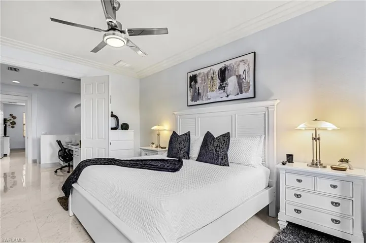 Bedroom featuring crown molding, a desk, a ceiling fan, and light marble finish flooring