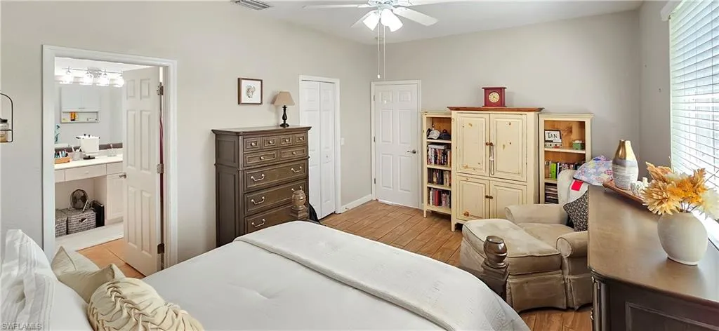 Bedroom featuring connected bathroom, light wood-style flooring, a ceiling fan, visible vents, and baseboards