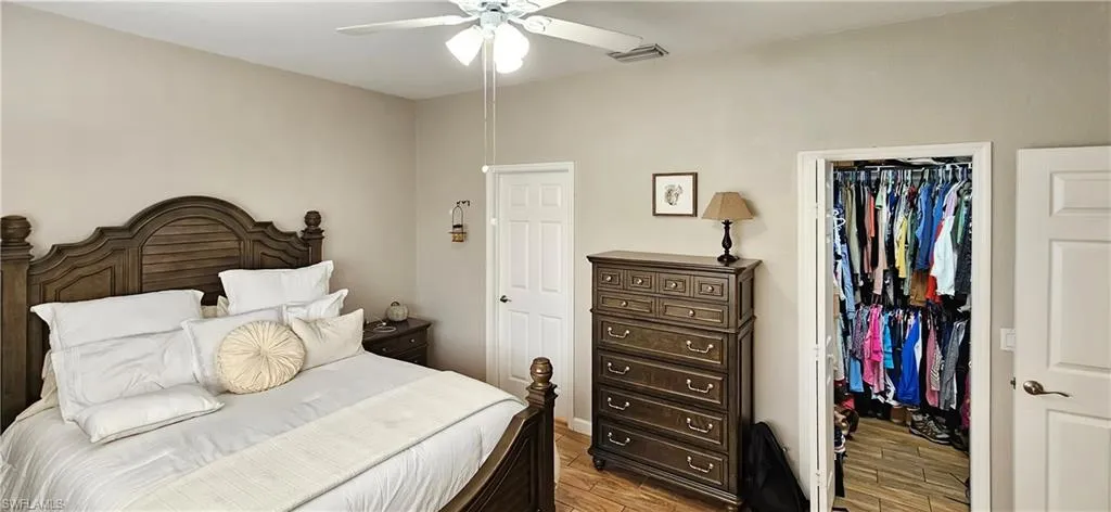 Bedroom featuring visible vents, a closet, a walk in closet, and light wood-style floors