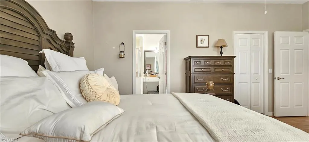 Bedroom with ensuite bath, a closet, and wood finished floors