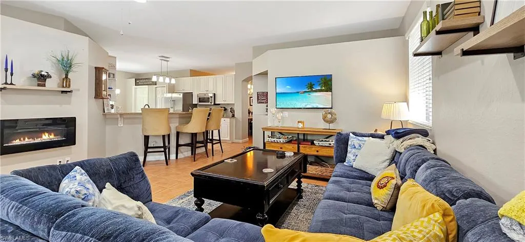 Living room featuring light tile patterned floors and a glass covered fireplace