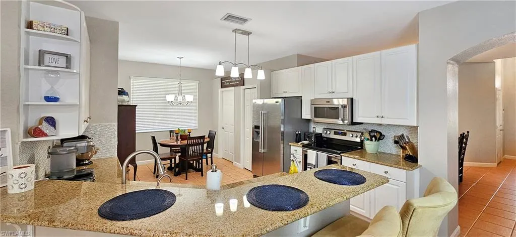 Kitchen featuring light tile patterned floors, arched walkways, appliances with stainless steel finishes, light stone countertops, and backsplash