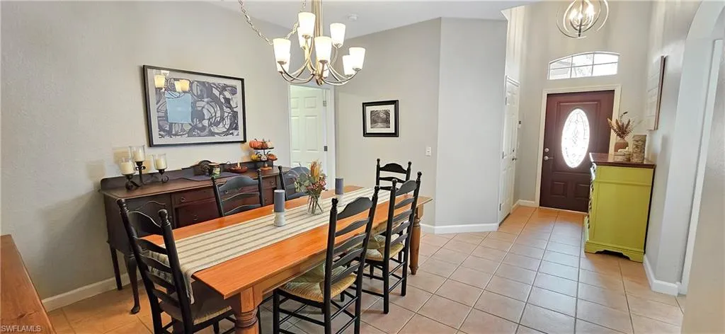 Dining room with an inviting chandelier, baseboards, and light tile patterned floors