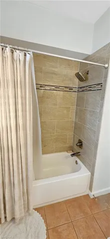 Bathroom featuring shower / bath combination with curtain and tile patterned floors