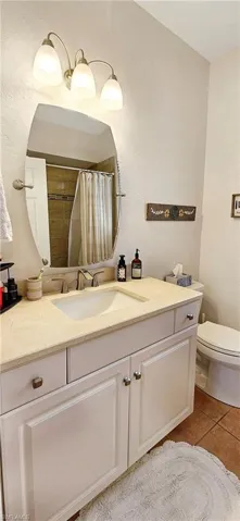 Bathroom featuring a shower with shower curtain, tile patterned floors, vanity, and toilet