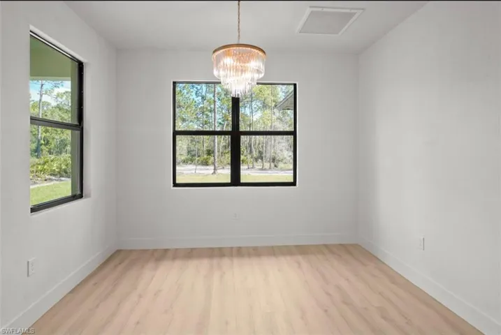 Empty room with a chandelier and light wood finished floors