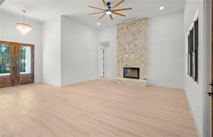 Unfurnished living room with light wood-style floors, french doors, a ceiling fan, recessed lighting, and a fireplace
