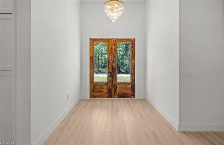 Foyer entrance featuring light wood-style floors, a chandelier, and french doors