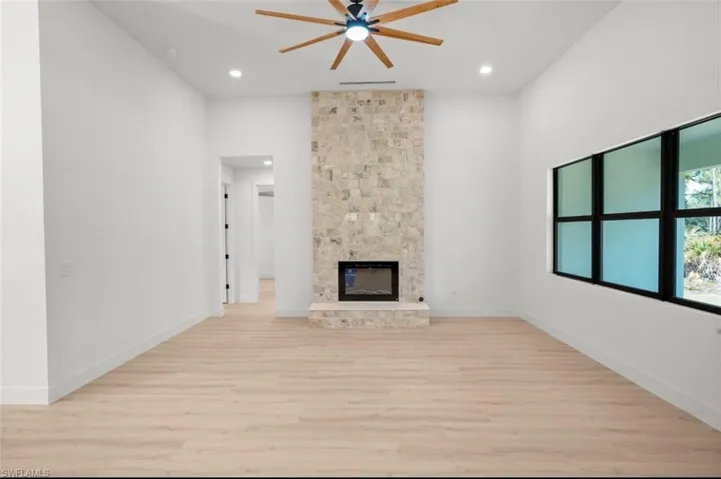 Unfurnished living room with light wood-style floors, a fireplace, a ceiling fan, and recessed lighting