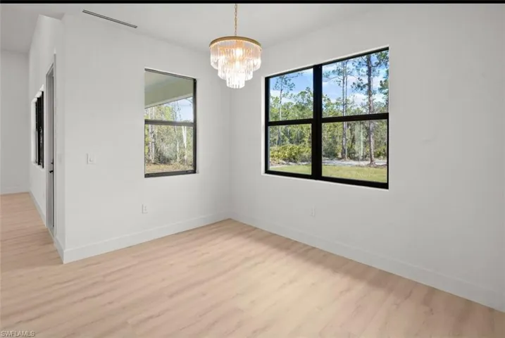 Empty room featuring a chandelier and light wood-style flooring