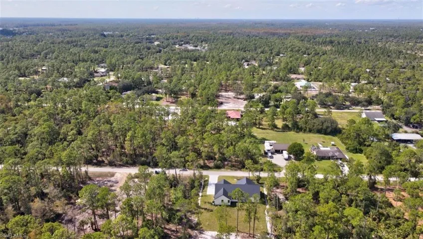 Aerial view of property and surrounding area featuring a forest