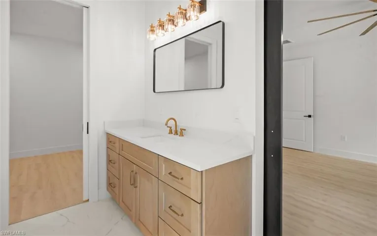 Bathroom featuring vanity, a ceiling fan, and light wood-style flooring